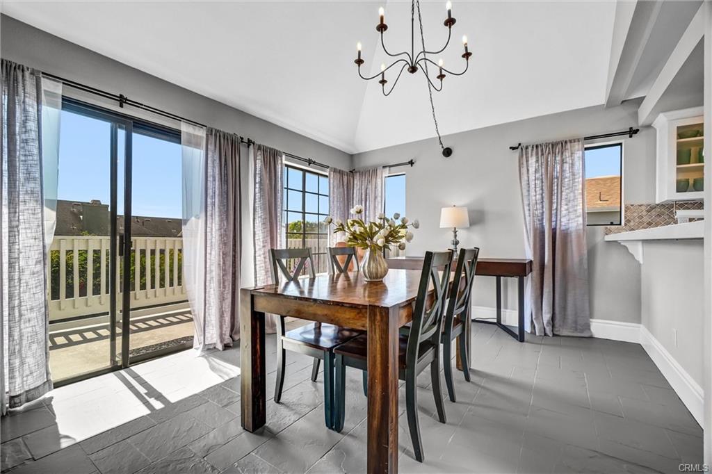 4682 Warner Ave #C304 — dining area with vaulted ceiling, chandelier, and balcony access