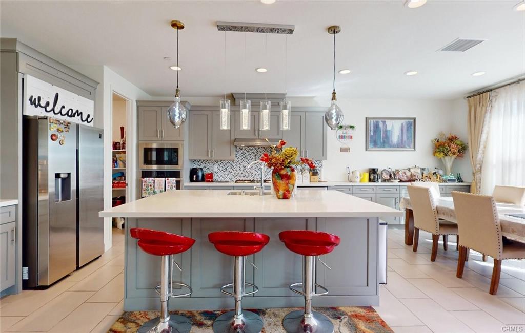 12954 Dahlia St — chef's kitchen with quartz island, shaker cabinetry, and stainless appliances