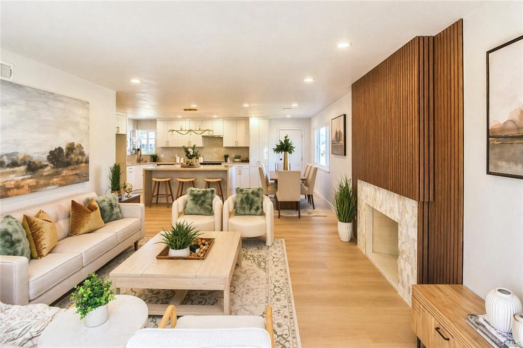 9142 Parliament Ave — open living room with fireplace, wood slat wall, and natural light